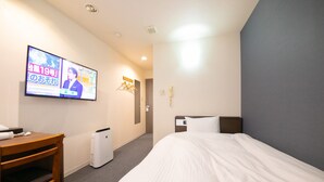 A hotel room with a bed, a desk, a TV, and a wall-mounted heater. - Hotel Nagisa (Beppu)