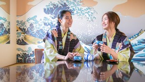 Two individuals in traditional attire sitting at a table with a decorative backdrop. - Hotel Nagisa (Beppu)