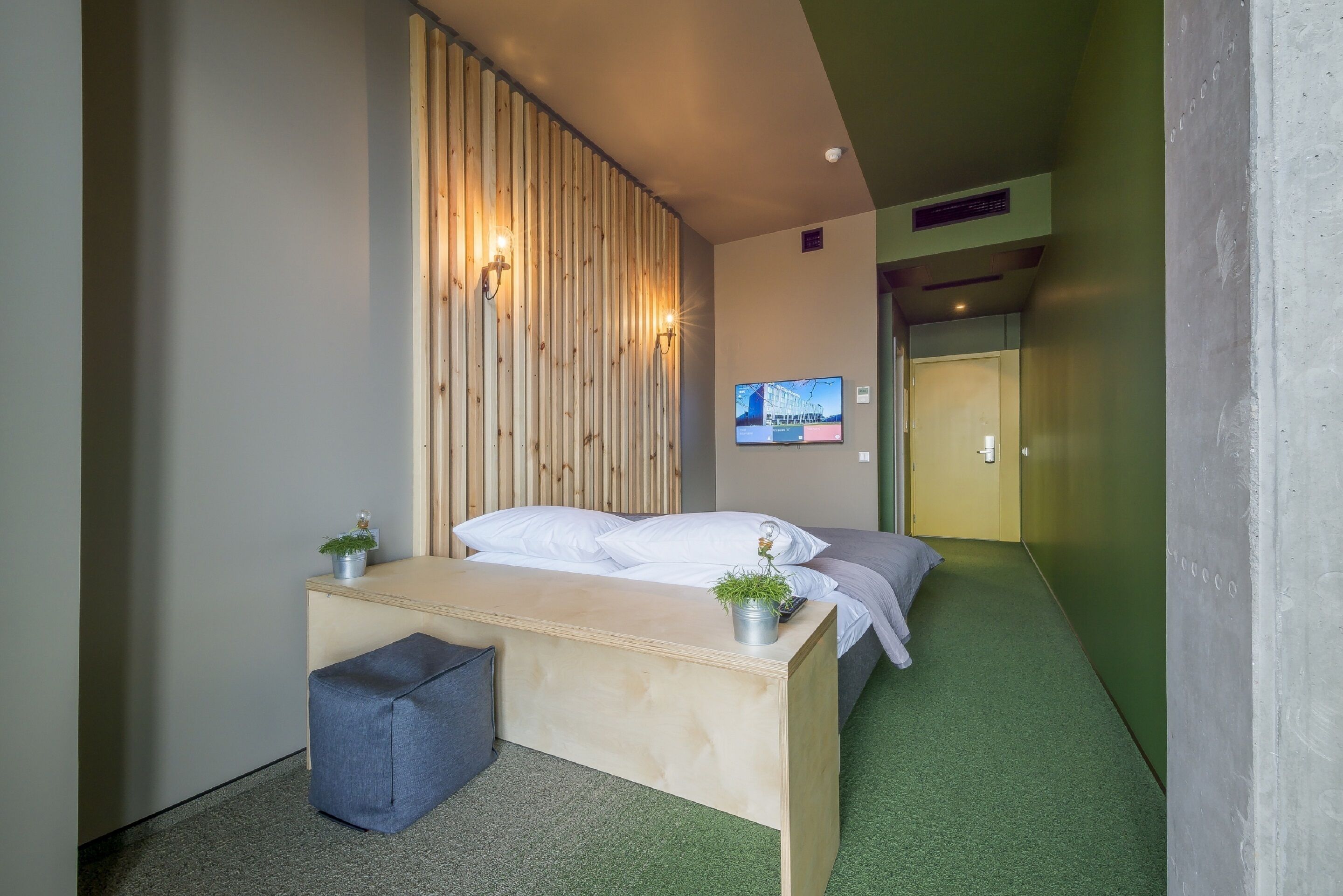Una habitación moderna con una cama, un escritorio y un televisor montado en la pared.