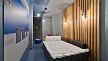 A modern hotel room with a bed, wooden panel wall, and a blue accent wall.