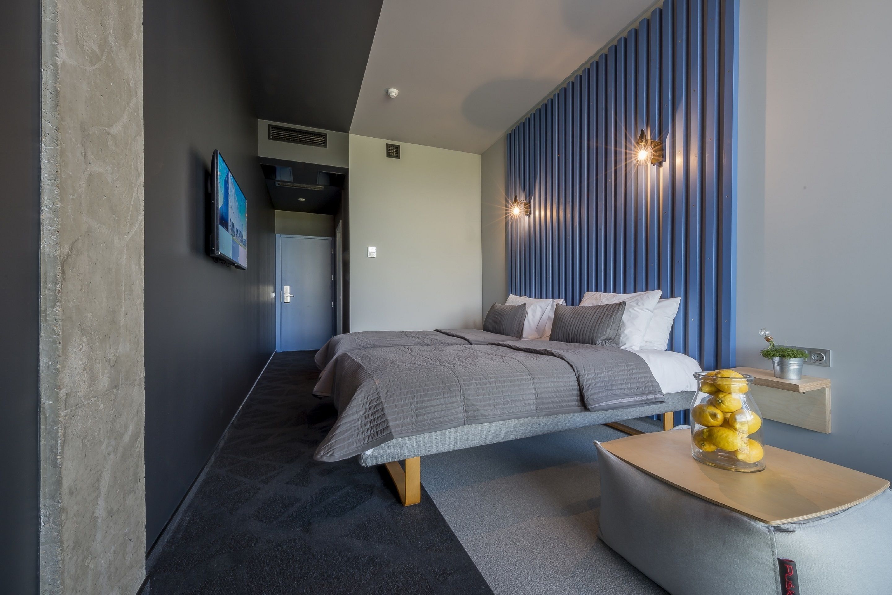 Un dormitorio moderno con cama, mesita de noche y lámpara de pared.