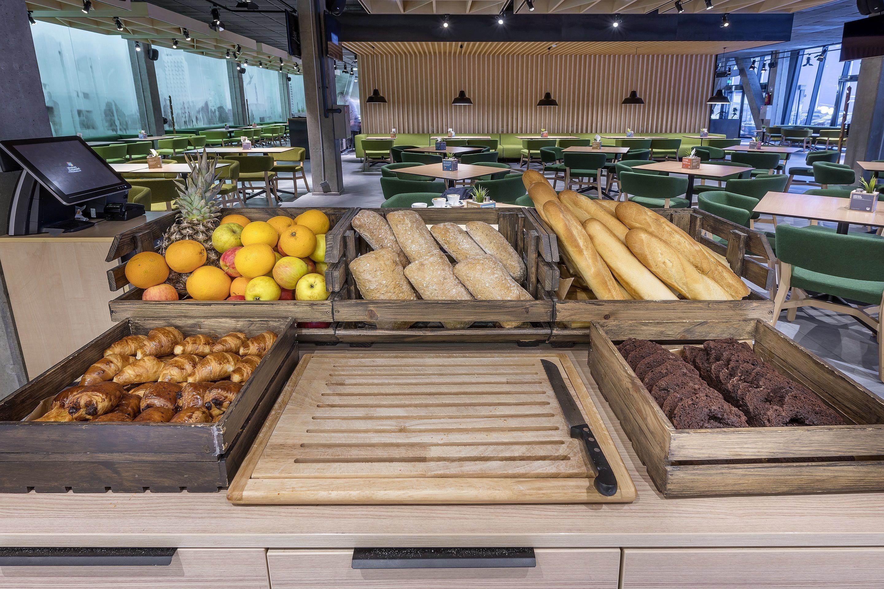 A bakery display with various baked goods and fruits in a modern cafe setting.