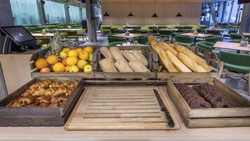 Mostrador de panadería con diversos productos horneados y frutas en un moderno café.