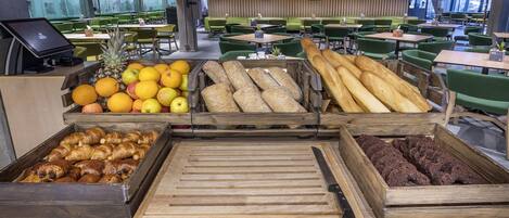 Mostrador de panadería con diversos productos horneados y frutas en un moderno café.