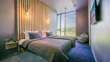 Ein modernes Schlafzimmer mit zwei Betten, einer Wand aus Holzlatten, einem kleinen Nachttisch, einem Sitzsack und einem an der Wand montierten Fernseher.