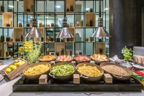 A buffet with various food items and a background of shelves with jars. - Urbihop Hotel (Vilnius)
