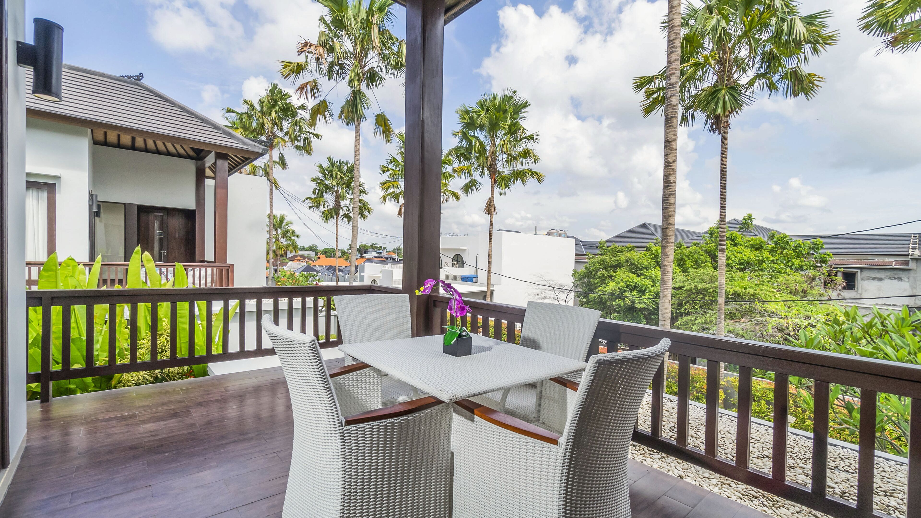 A balcony with wicker furniture, a table, and a potted plant.