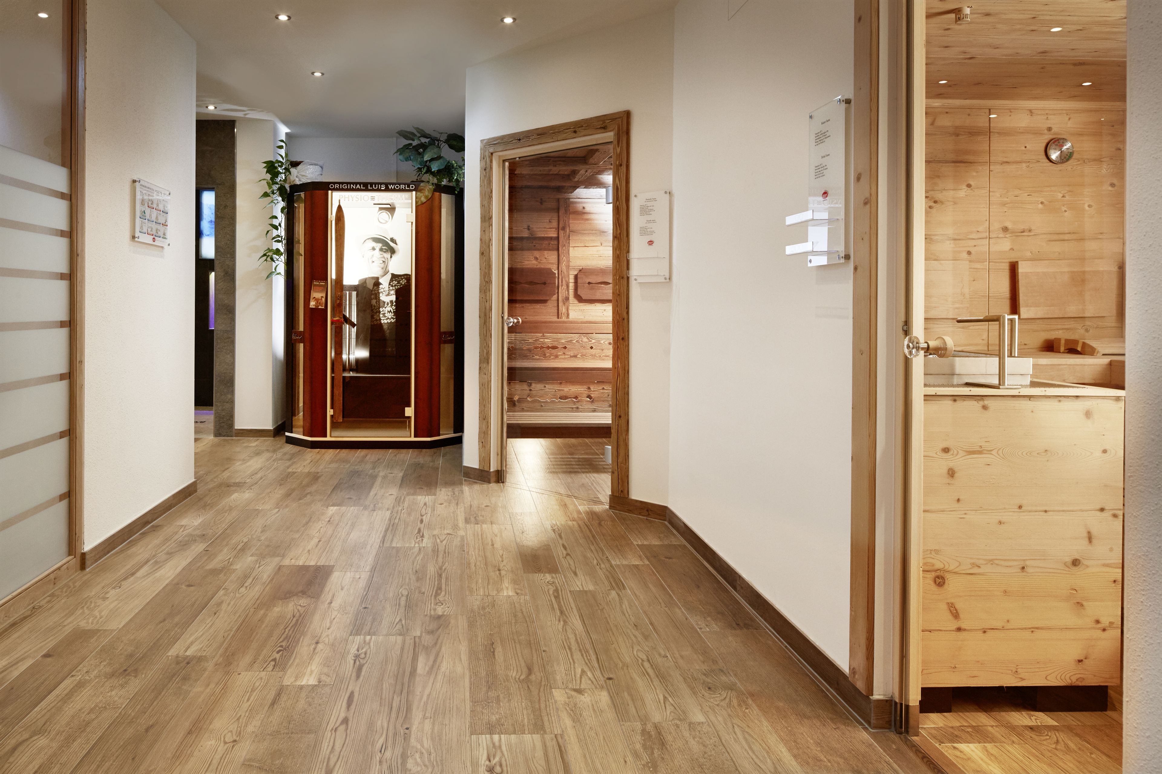 Un corridoio con pavimento in legno che conduce a una stanza con una porta in legno.