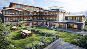 Een hotel met meerdere verdiepingen, met terras, zwembad en een berg op de achtergrond.