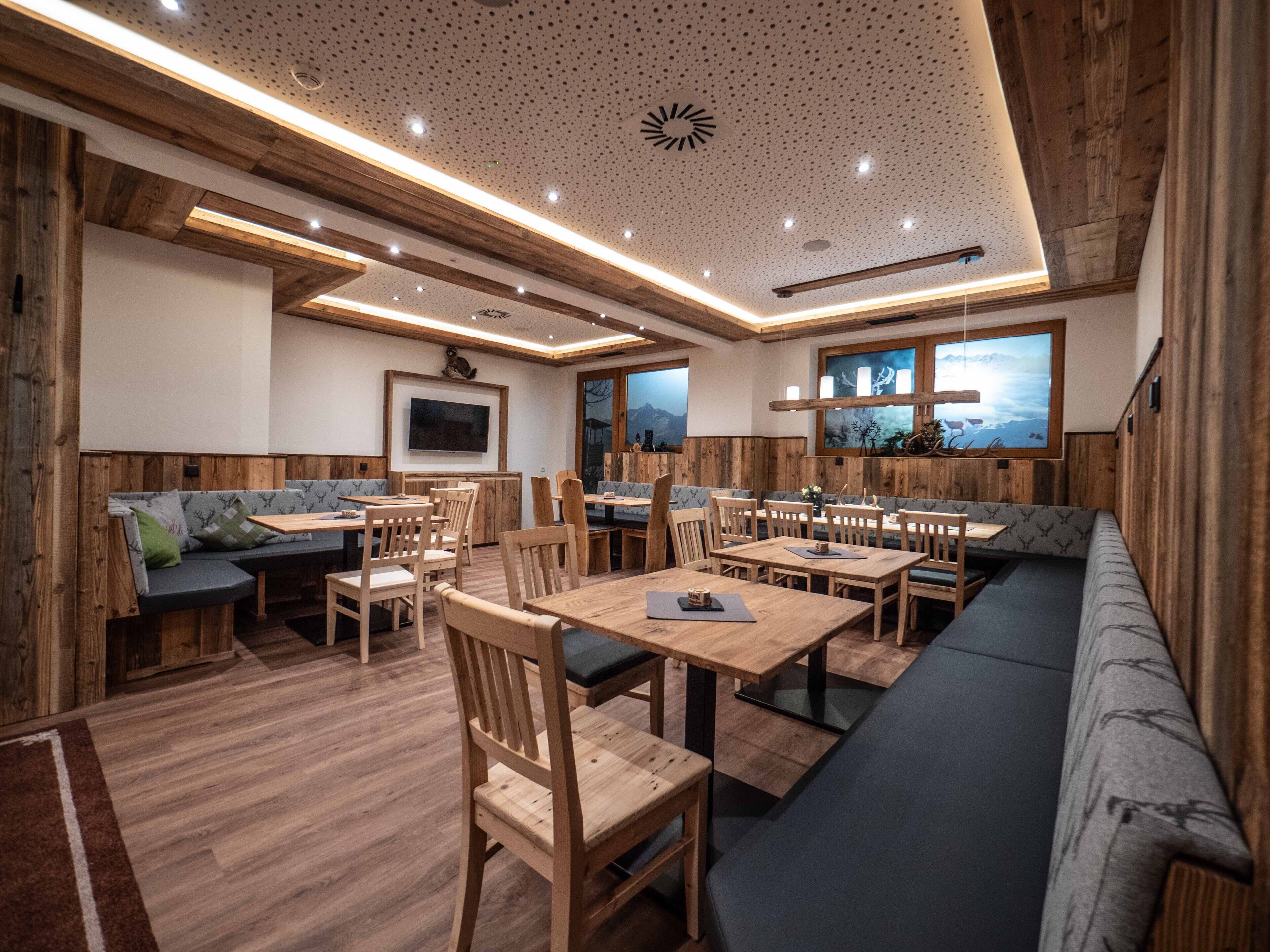 A restaurant with wooden paneling, multiple seating areas including tables and booths, and a large window with a mountain view.