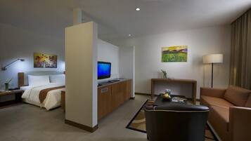 Una habitación de hotel con una cama, un escritorio con computadora, un sofá y una mesa de centro.