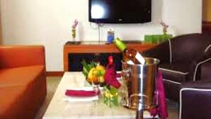 Una sala de estar con un televisor de pantalla plana montado en la pared, una chimenea, una mesa de centro con un jarrón de flores y un sofá.