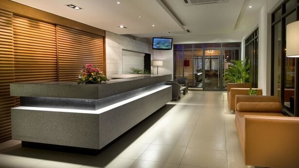 Un área de recepción moderna con mostrador, asientos y televisor.