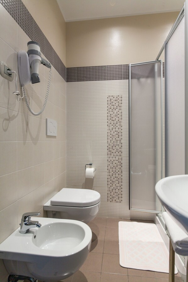 A bathroom with a bidet, toilet, and a shower area. - Hotel La Grotta (San Marino)