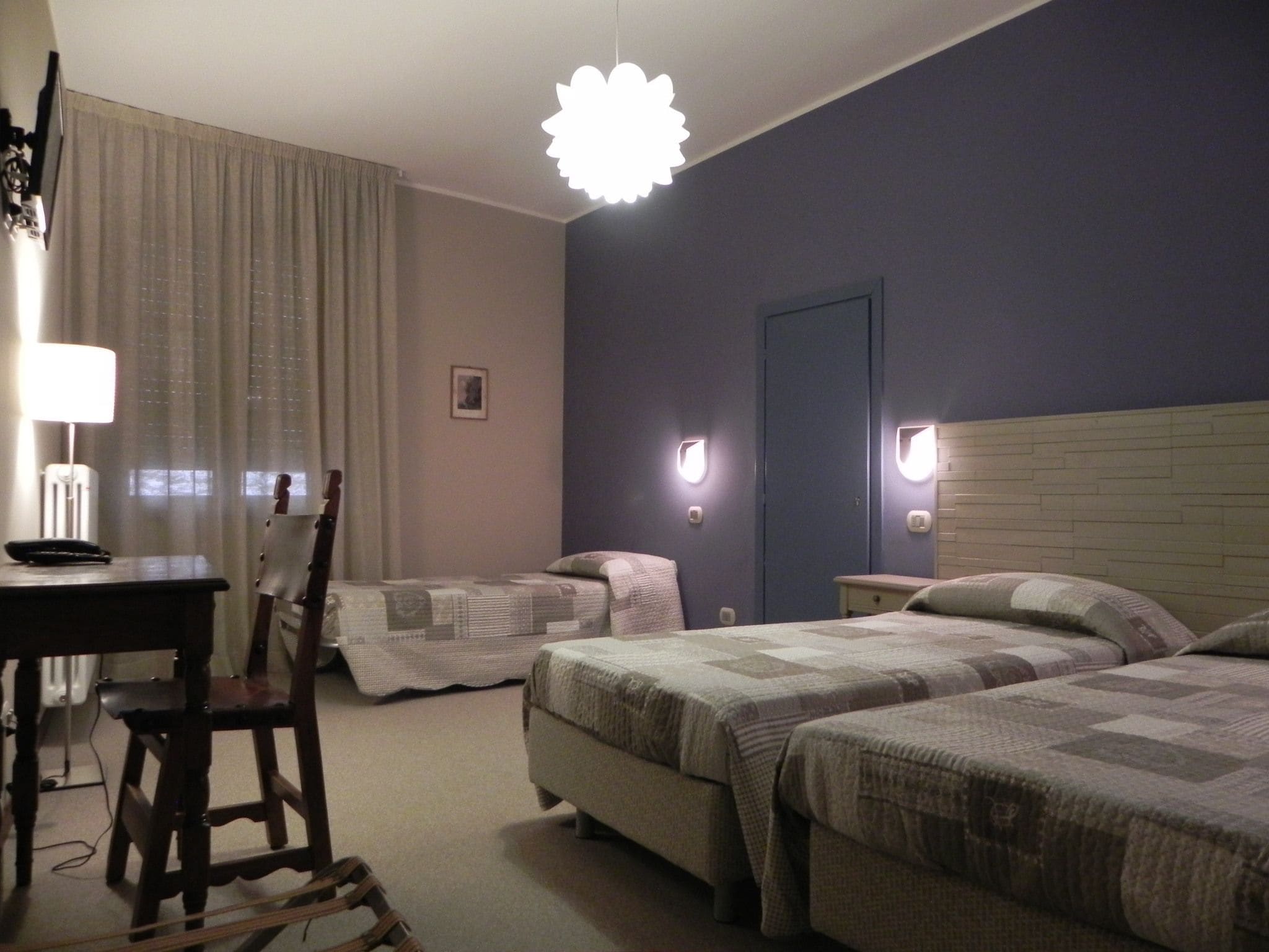 Habitación de hotel con dos camas, un escritorio, una silla, una lámpara y una lámpara del techo.