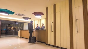 A hotel reception area with a reception desk, a man with a suitcase, and three staff members. - Memoire Hornbill Hotel Kuching Sarawak (Kuching)
