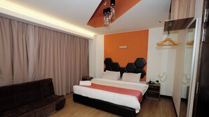 A modern hotel room with a large bed, a dark brown sofa, a wooden floor, and a mirror on one wall. - Memoire Hornbill Hotel Kuching Sarawak (Kuching)