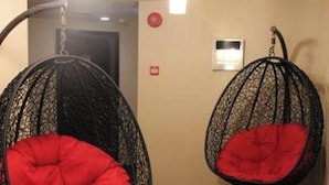 Two black wire-framed hanging chairs with red cushions in a room with wooden flooring and a light-colored wall. - Memoire Hornbill Hotel Kuching Sarawak (Kuching)