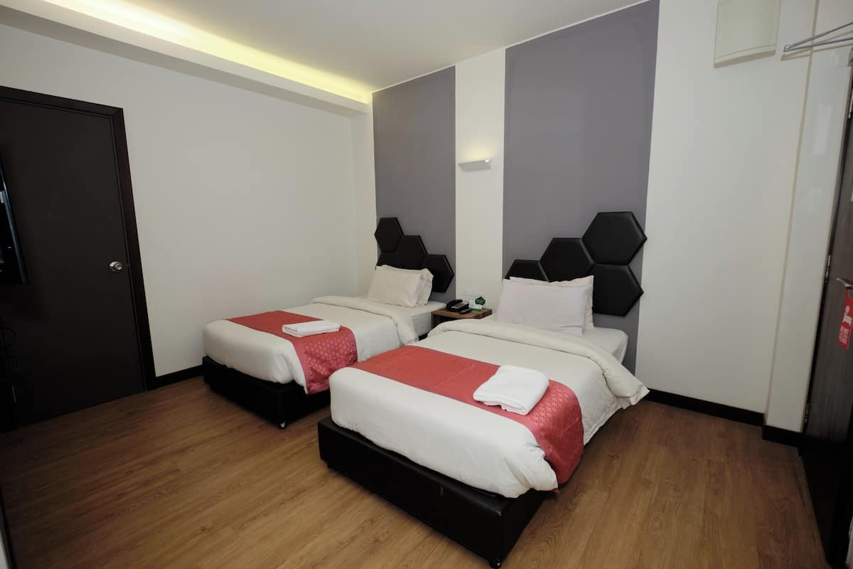 A hotel room with two beds, wooden flooring, and a modern design.