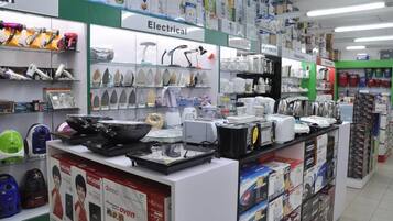 A store with various household appliances and electronics on display, including irons, kettles, and a microwave.
