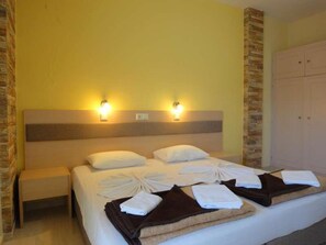 A hotel room with a bed, two wall-mounted lights, a wooden headboard, and a wardrobe.