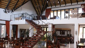 A spacious interior with a central staircase, multiple dining areas, and a balcony. - La Rochelle (Tsumeb)