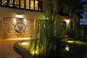 Ein Gebäude mit einer steinernen Fassade, ein Logo mit Reiter und Pferd sowie ein Wasserspiel mit hohem Gras.