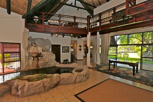 Eine geräumige Lobby mit einem großen Fenster, einem Wasserspiel aus Stein und einer Holzbank.