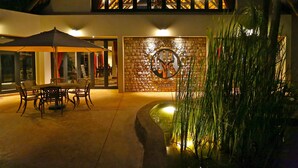 An outdoor patio with a table and chairs, a decorative wall, and a water feature. - La Rochelle (Tsumeb)