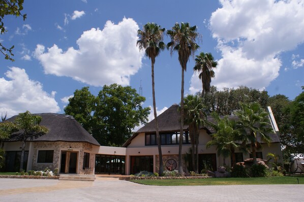 A building with a thatched roof, palm trees, and a clear sky.