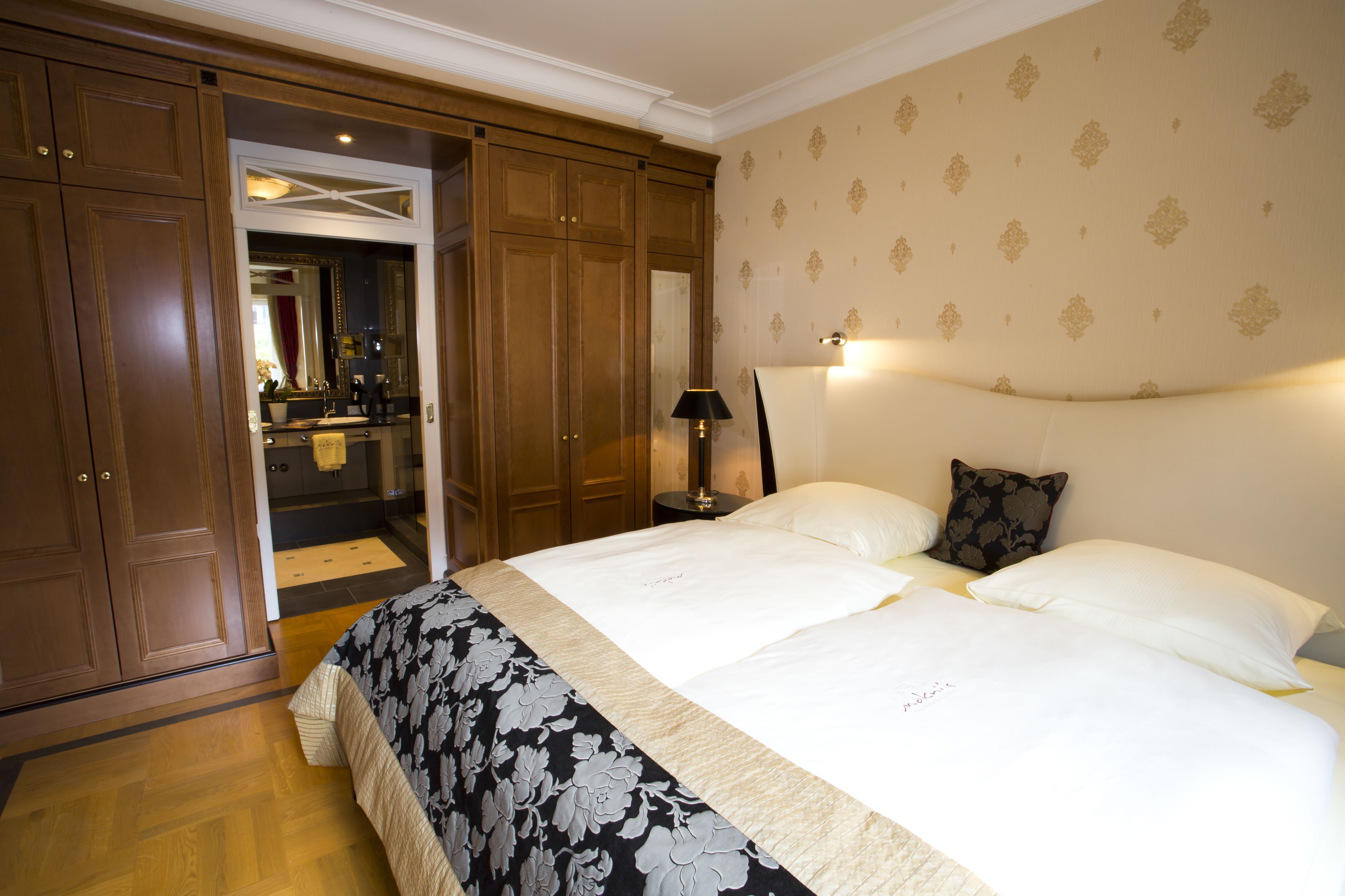 A hotel room with a large bed, a nightstand, a mirror, and a wardrobe.