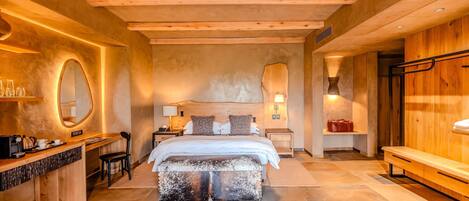 A modern bedroom with a large bed, wooden headboard, bedside tables, a desk, and a bench.