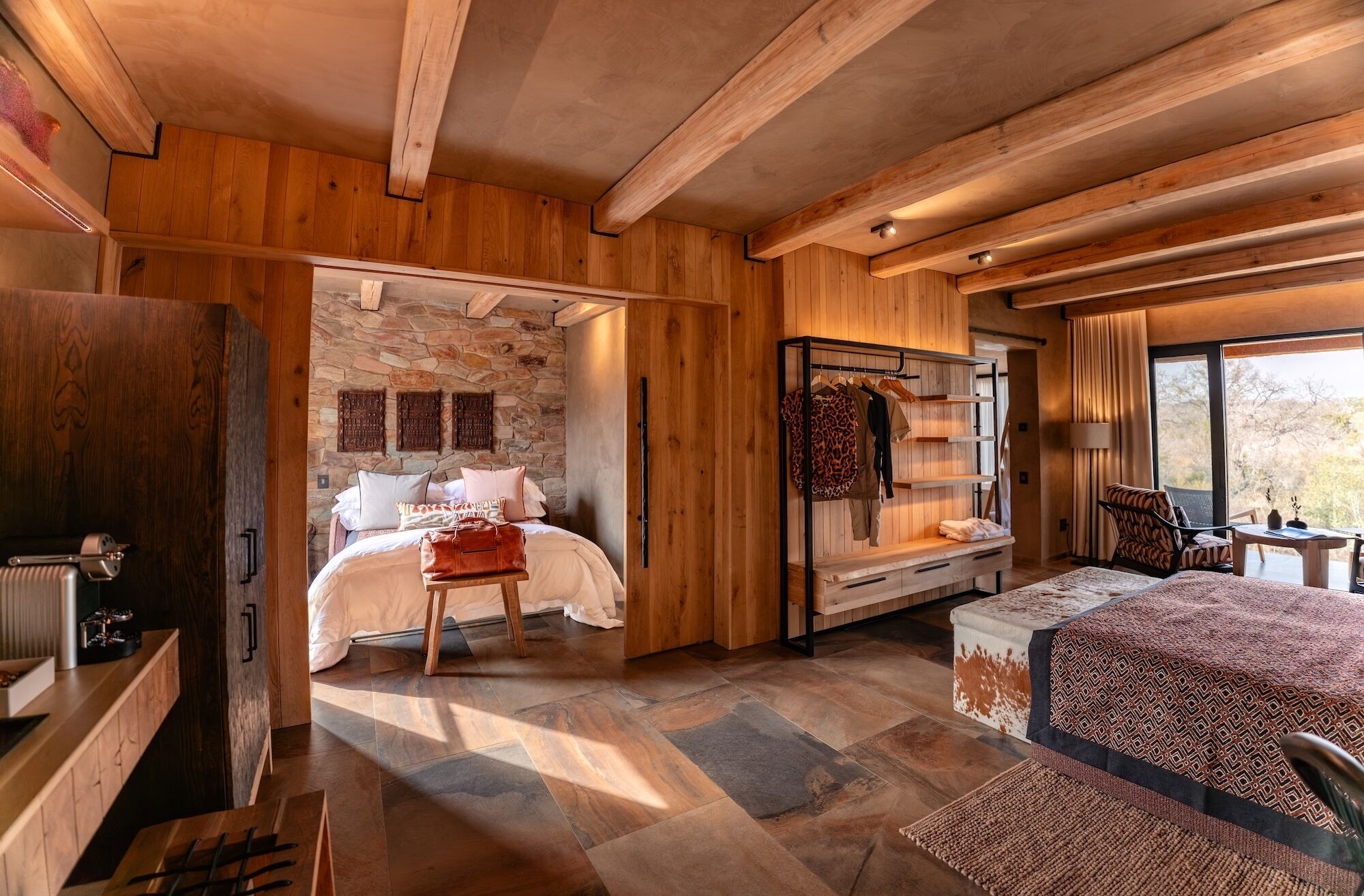 Ein Holzinnenraum mit einem Bett, einer Sitzecke und einer Steinwand.