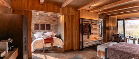 Un intérieur en bois comprenant un lit, un coin salon et un mur en pierre.
