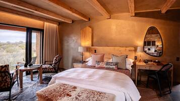 A bedroom with a large bed, a desk, a chair, and a mirror.
