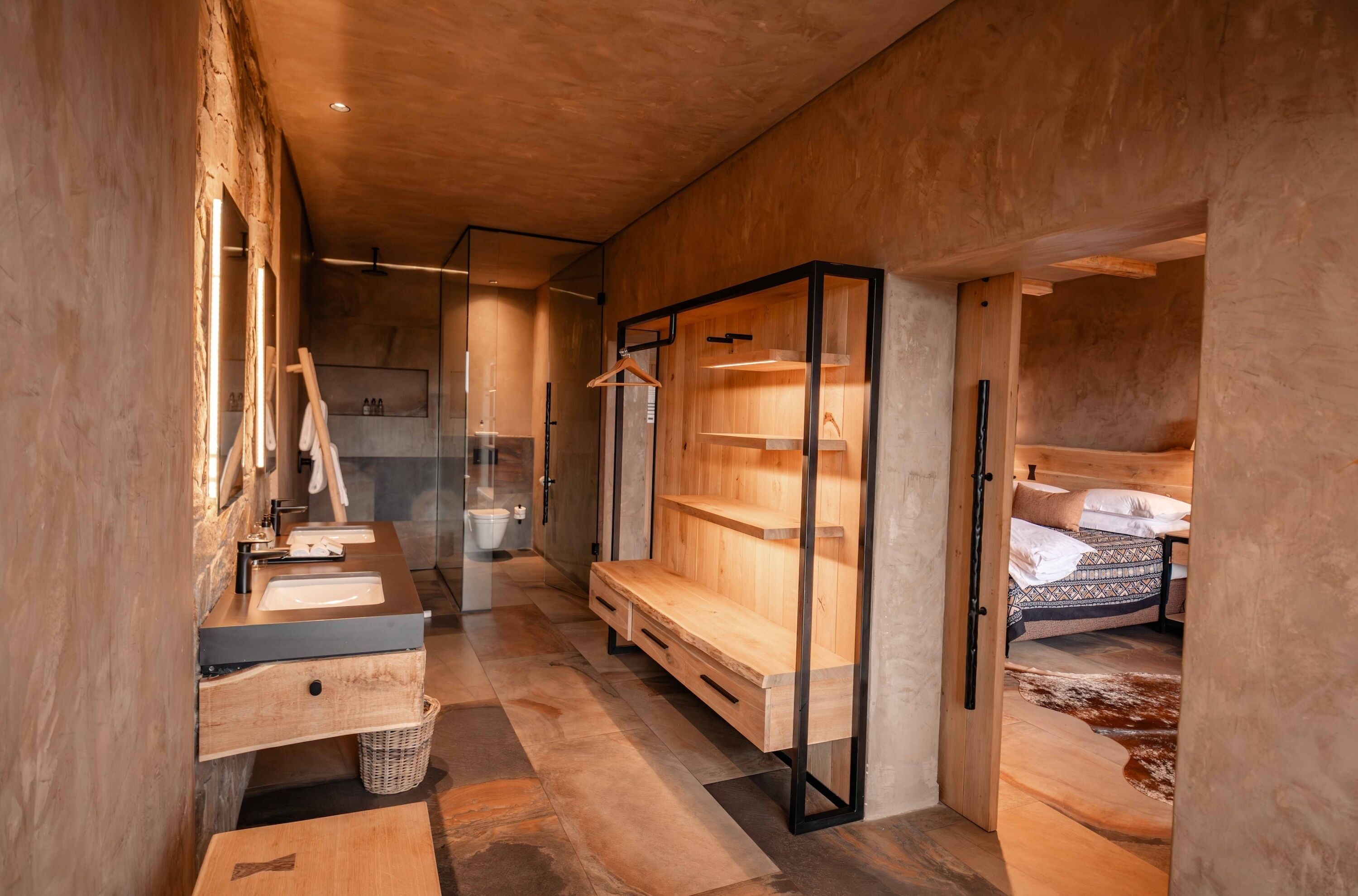 A modern bathroom with a wooden vanity, a bench, and a hanging rack.