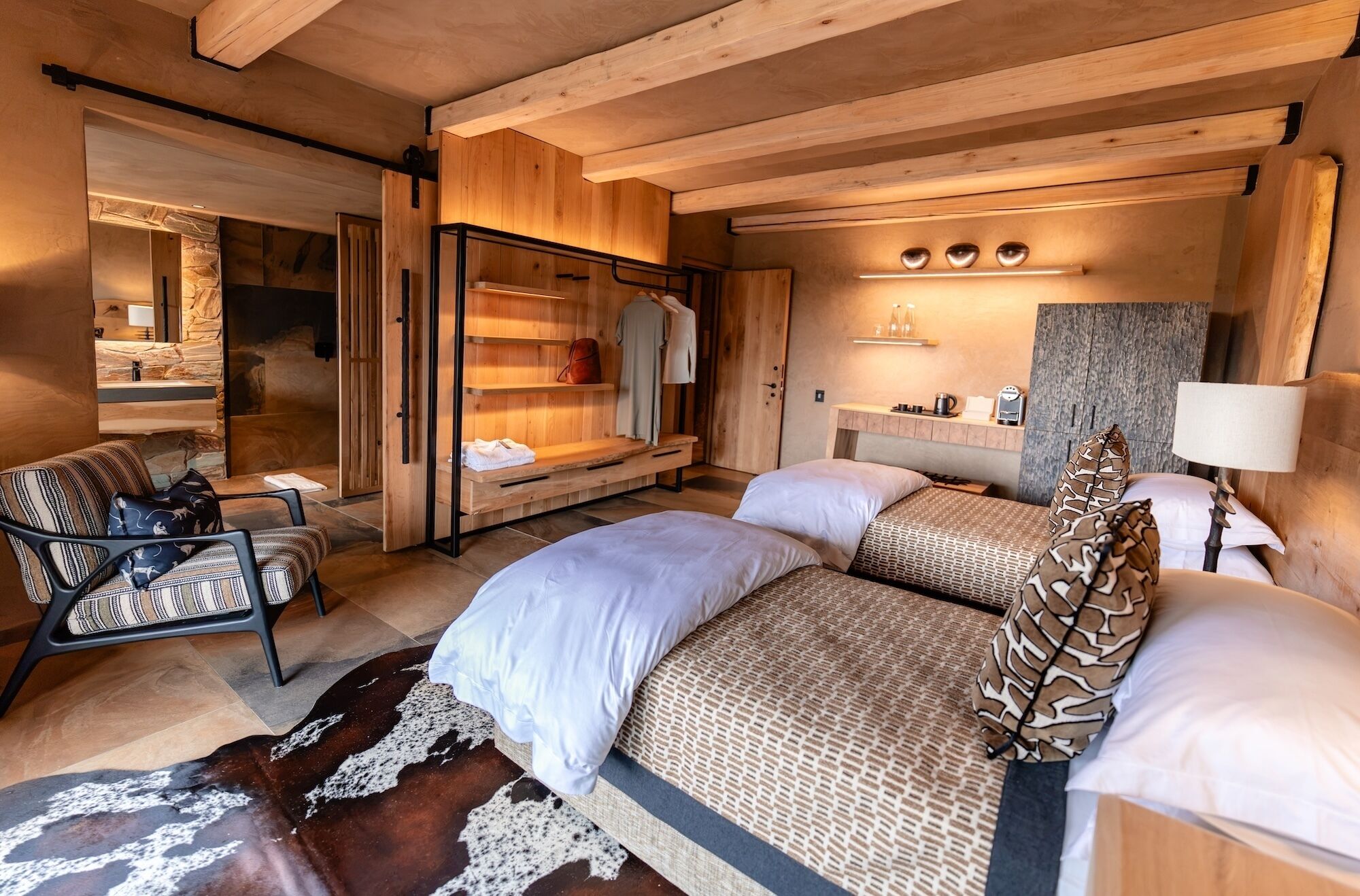 A cozy bedroom with a bed, two bedside tables, a chair, and a hanging light fixture.