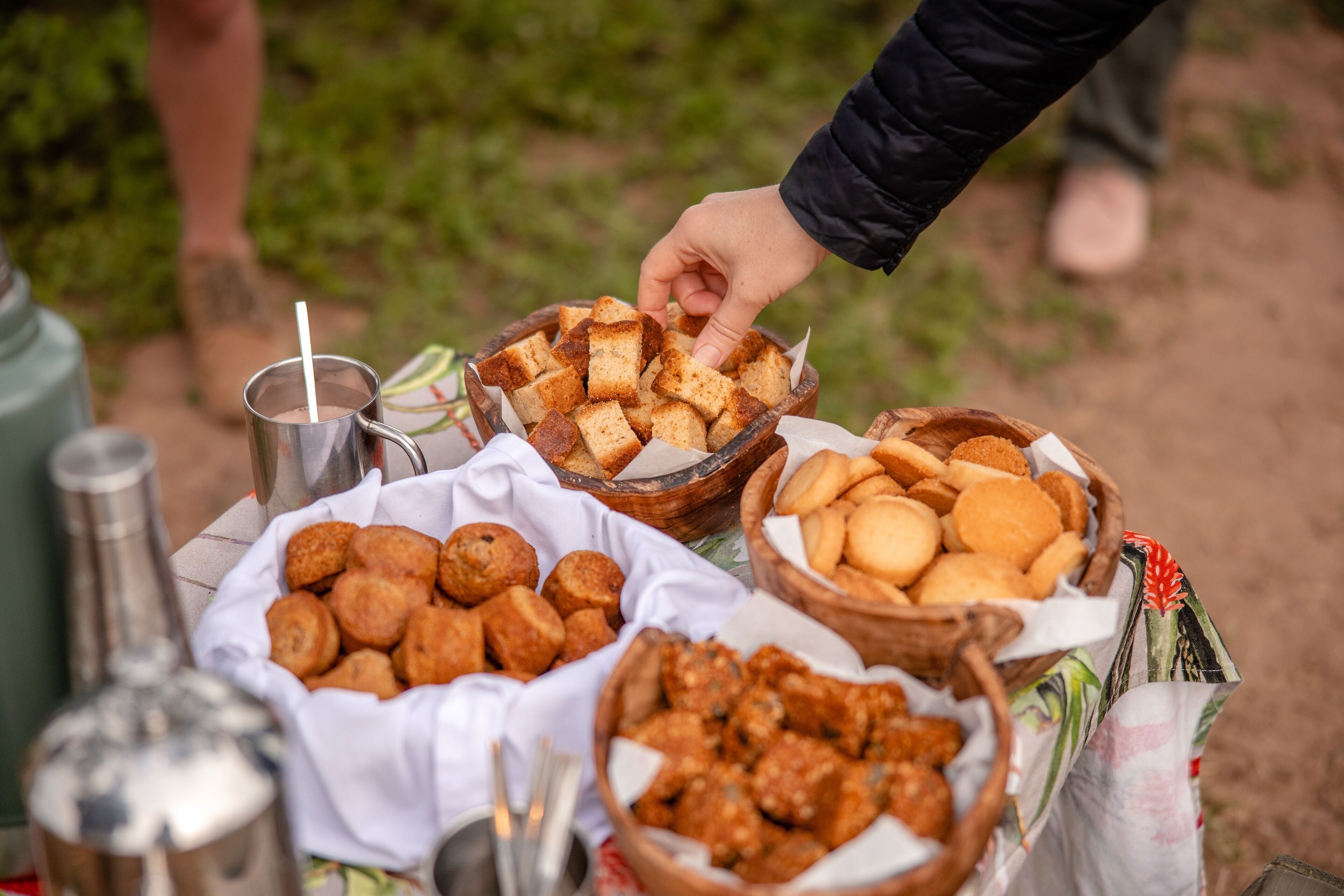 Una mesa con diferentes alimentos y una bebida, incluyendo pan, pasteles y una botella.