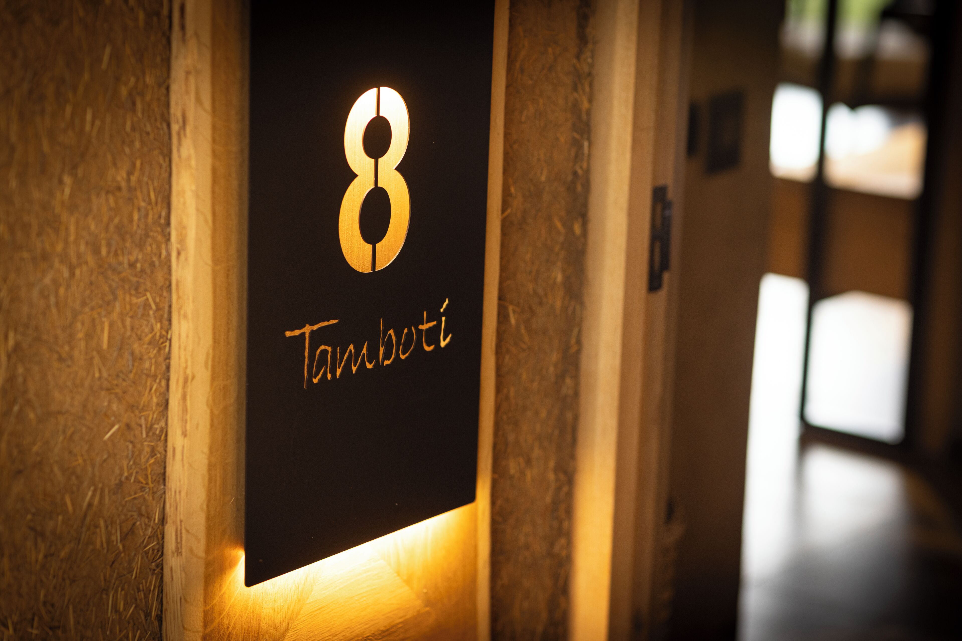 A hallway with a sign indicating room number 8 and the name 'Tambolt'.