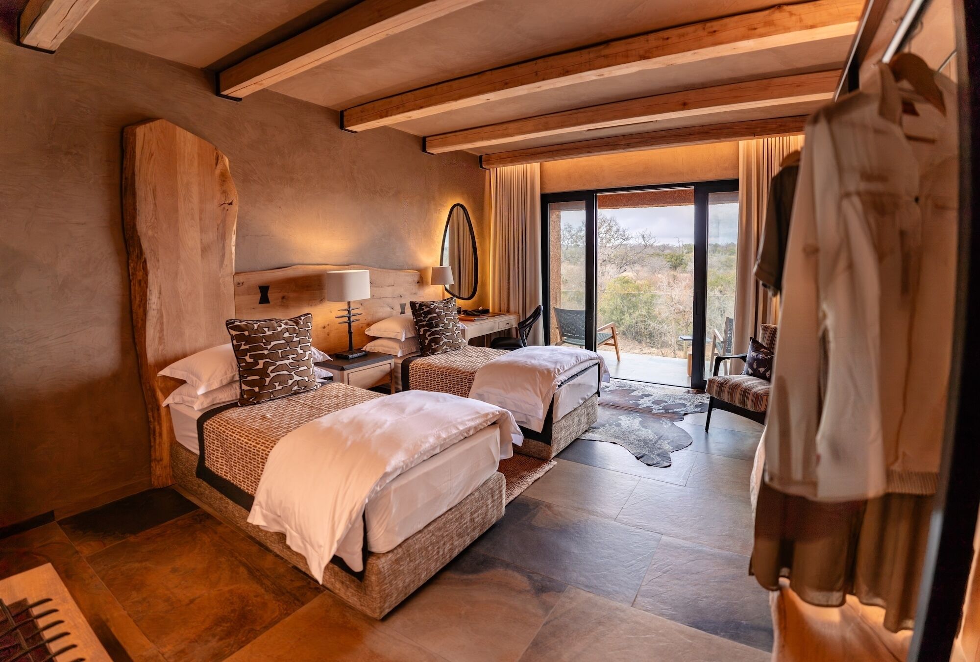 Habitación de hotel con dos camas, un ventanal grande y vistas al exterior.