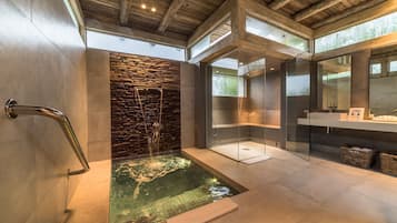 Enjoy a serene bathroom experience with a large glass-enclosed shower and water feature.
