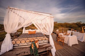 A bed with a canopy, a table with food, and a view of the landscape.
