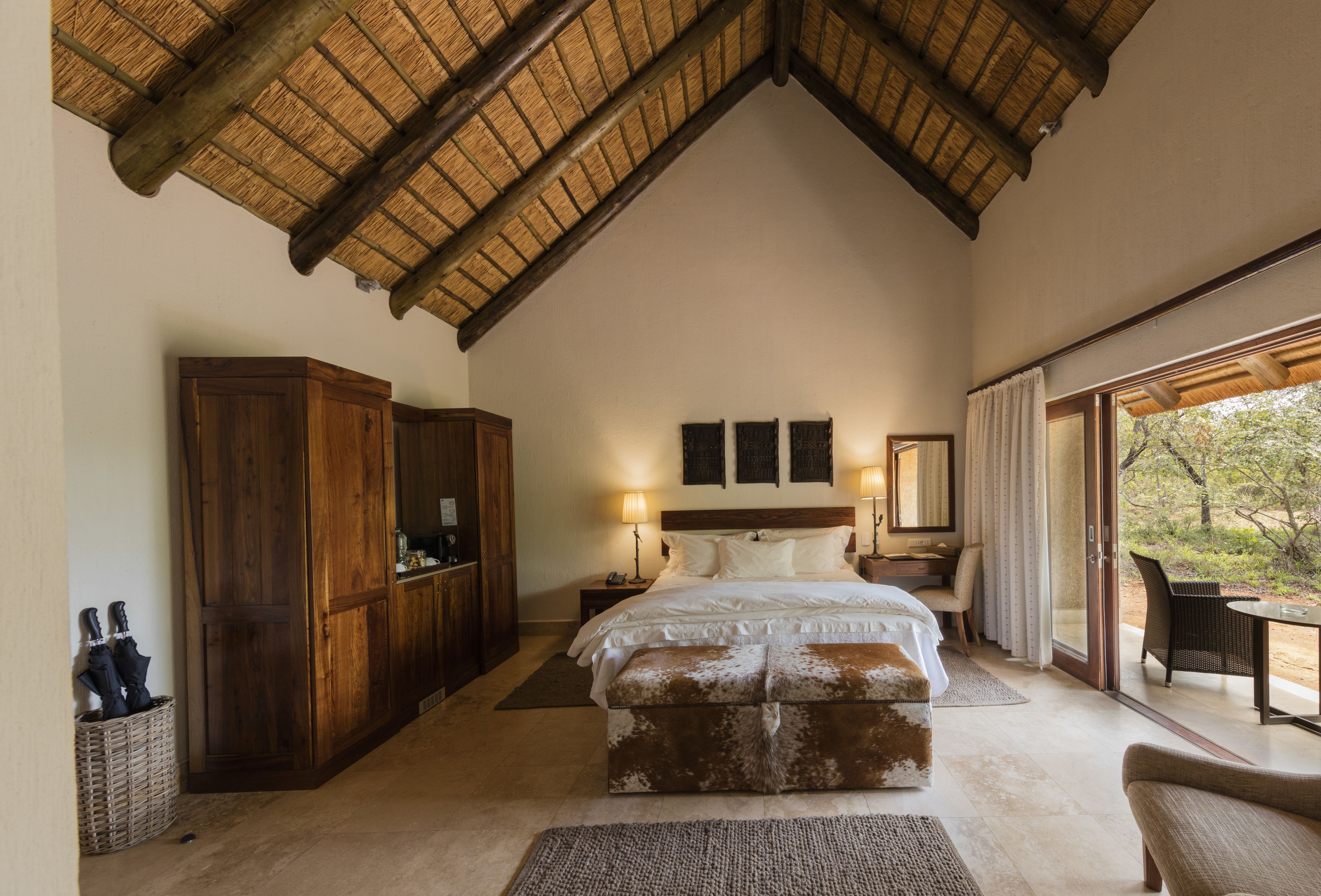 A bedroom with a large bed, wooden wardrobe, and a balcony with a view.