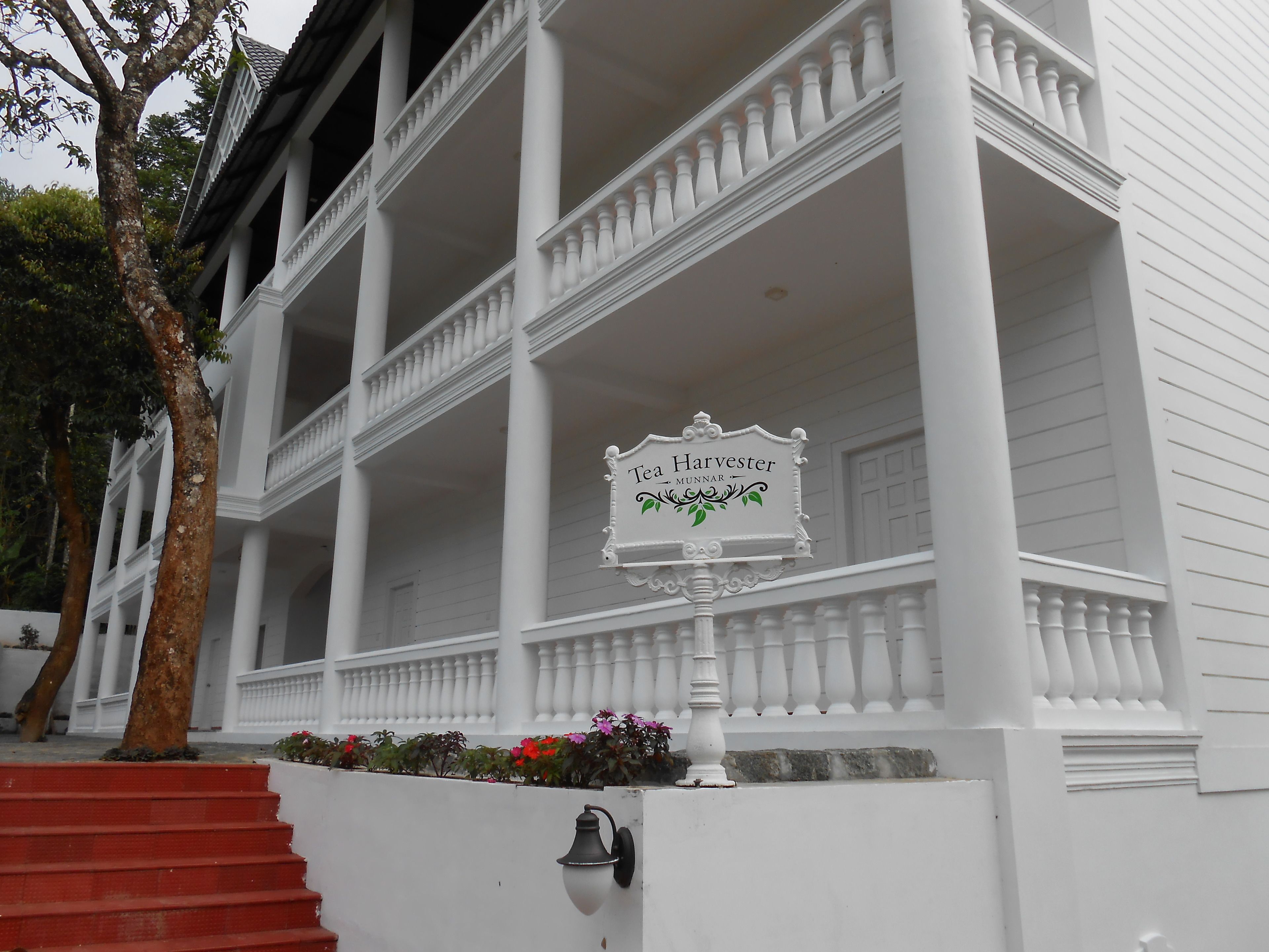 A white building with a sign reading "Tea Harvester Munnar".