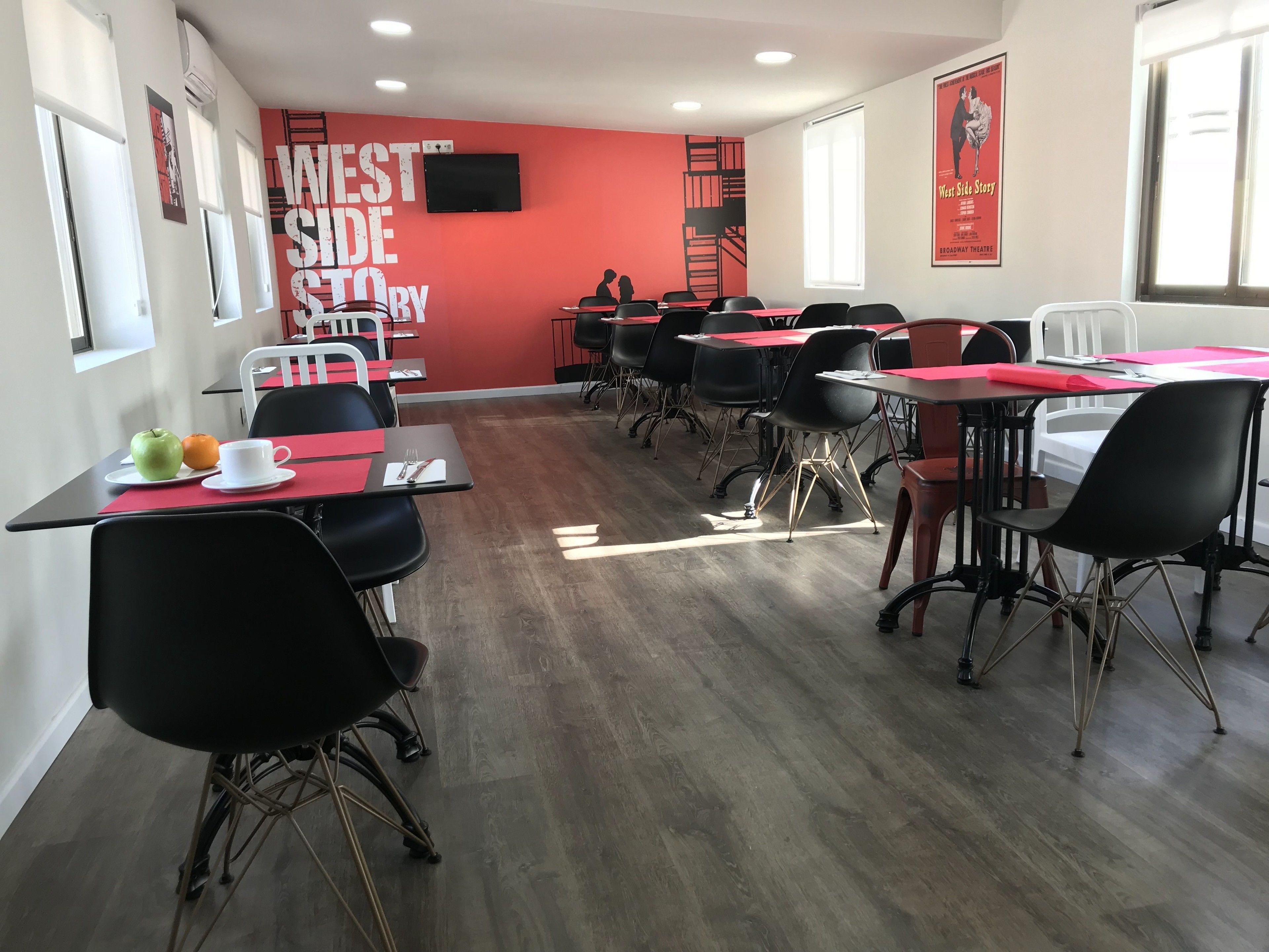Une salle de conférence équipée de tables et de chaises, d’un grand écran et de posters accrochés aux murs.
