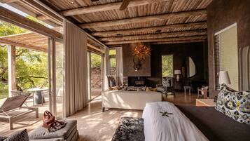 A spacious living area with a fireplace, comfortable seating, and large windows offering a view of the outdoors.