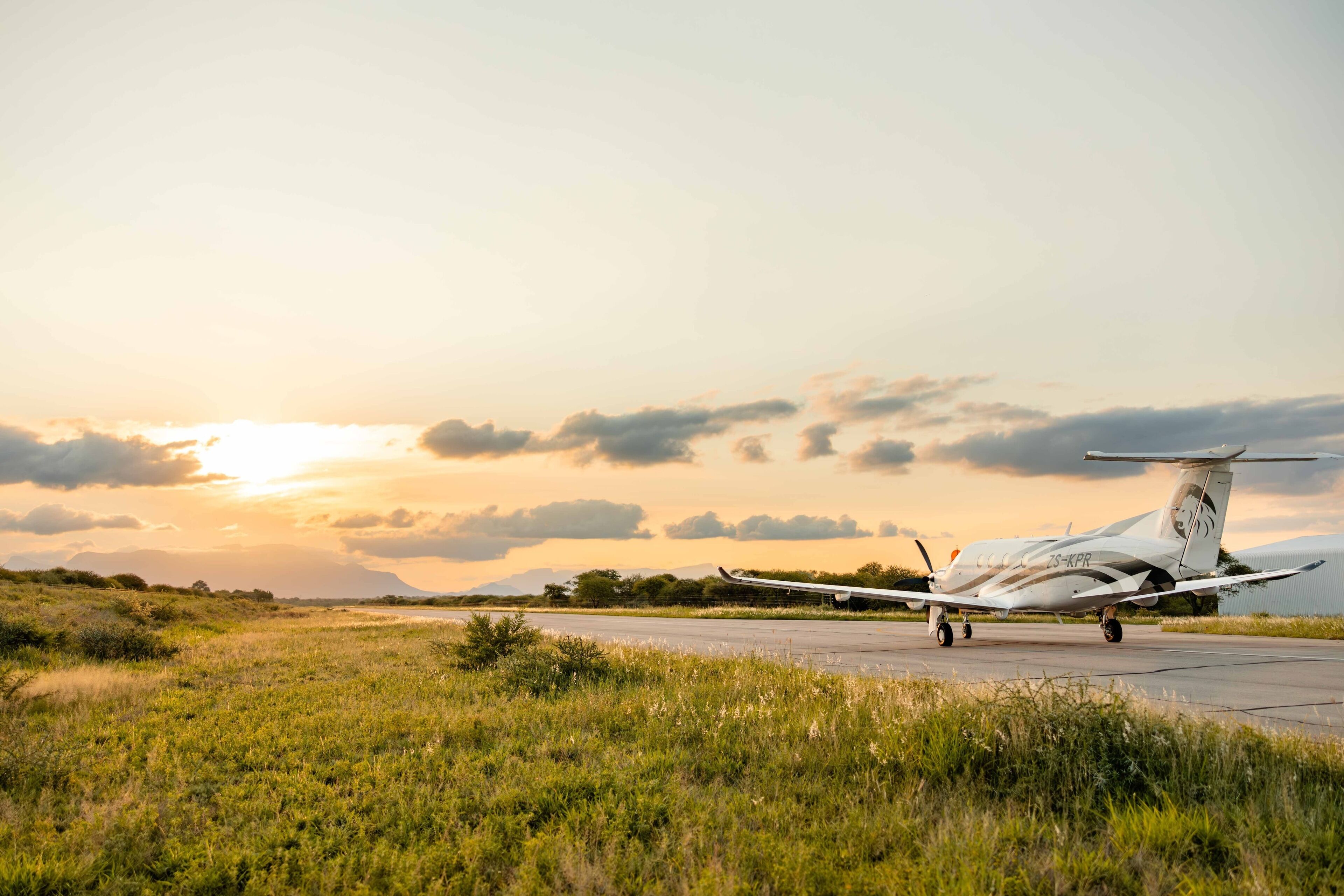 Un avión en la pista con un atardecer de fondo.