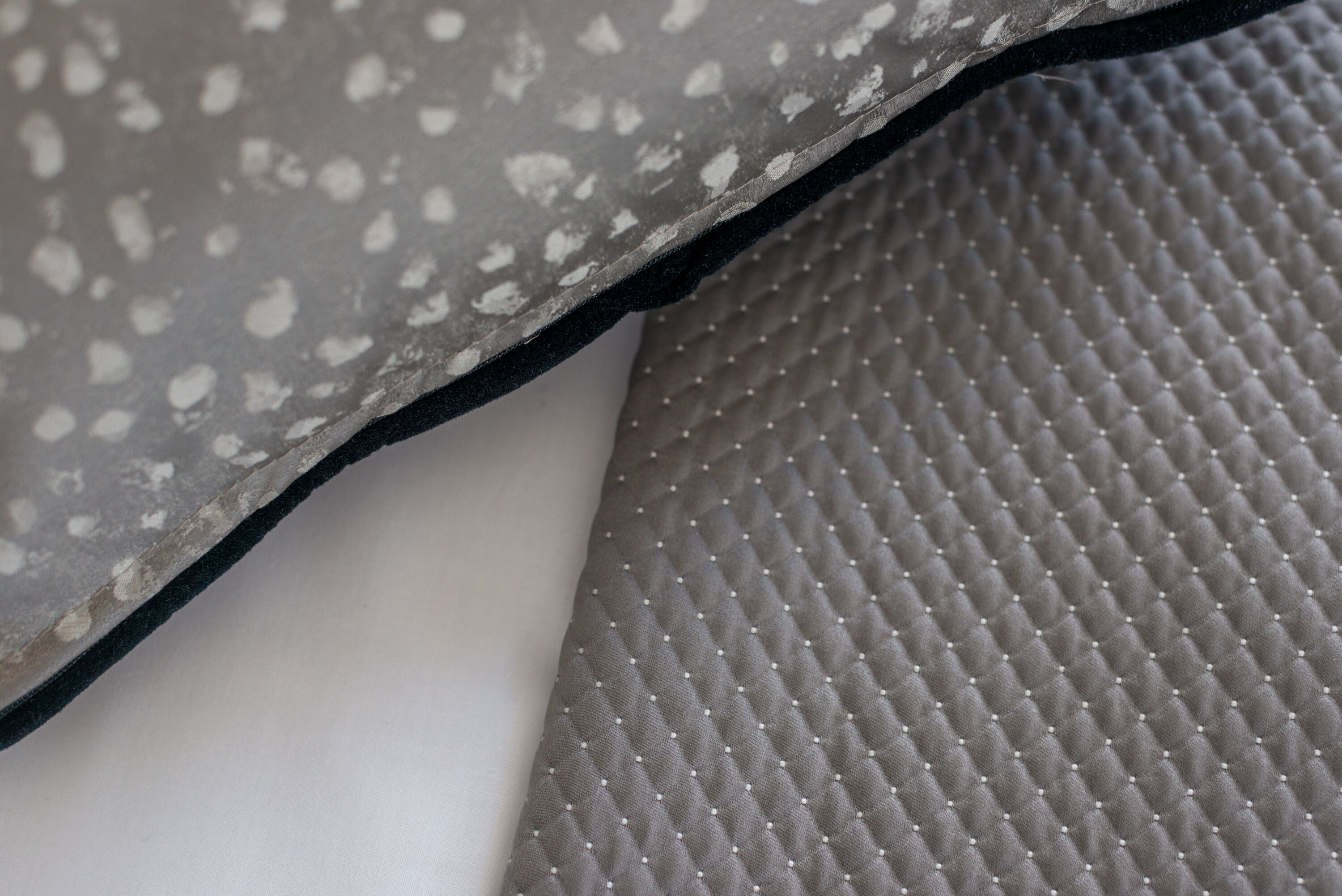 Een detail van een textiel met een patroon van kleine witte stippen en een zwarte rand.