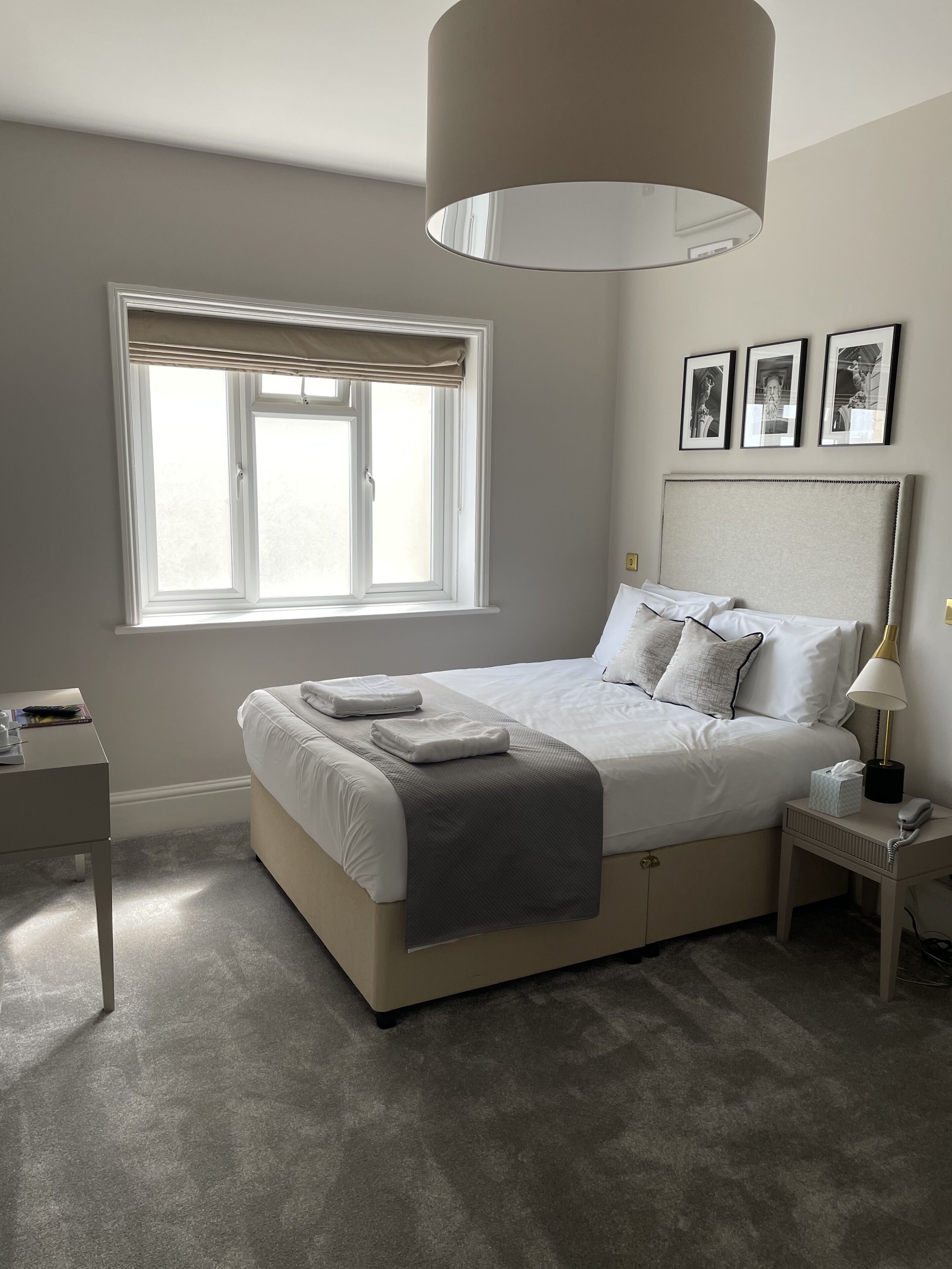 A bedroom with a bed, bedside tables, a window, and a lamp.