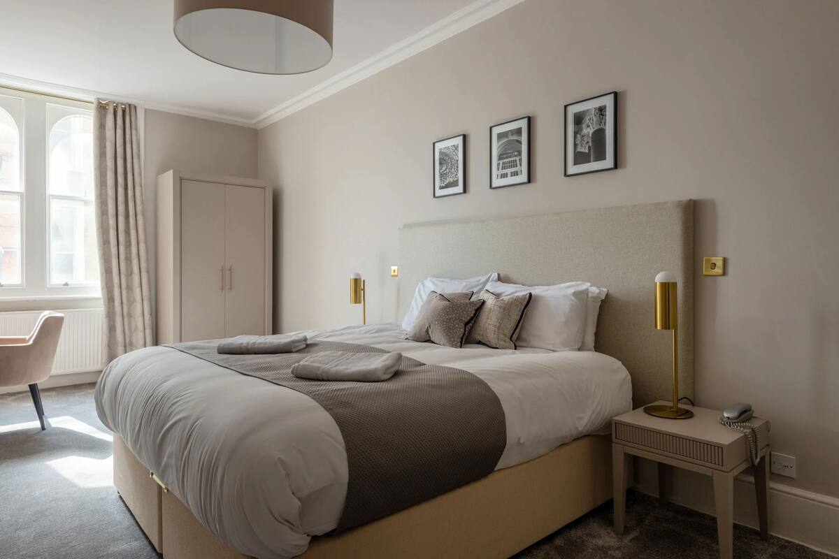 A neatly arranged bedroom with a large bed, bedside tables, and a chair.